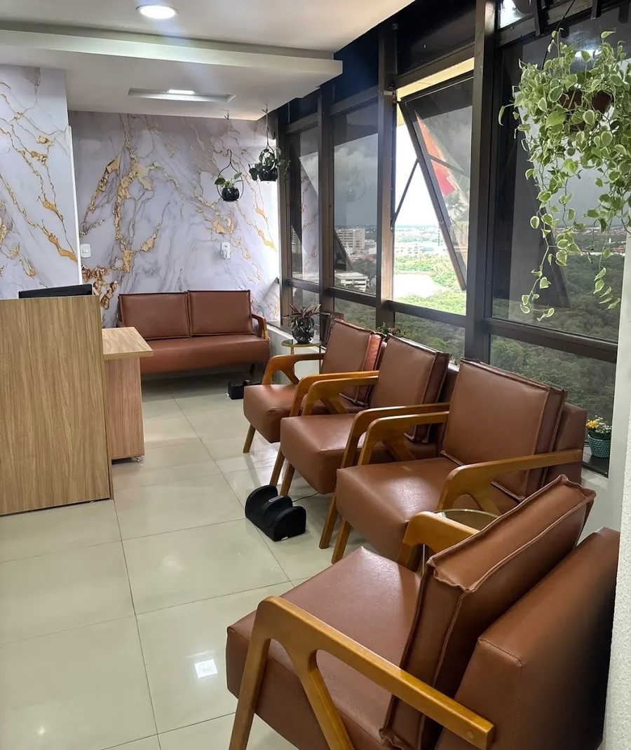 Recepção com poltronas de couro caramelo e parede de mármore